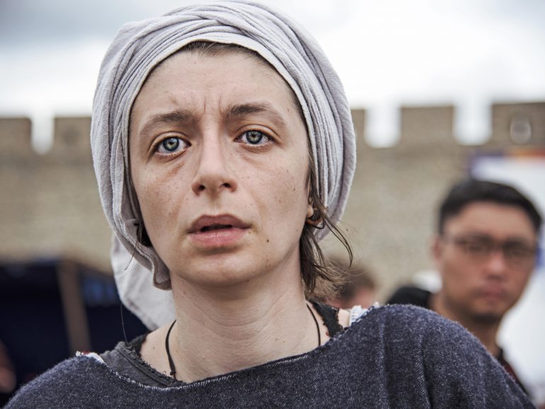 Portrait of a woman with a headscarf, expressing deep emotion against a blurred background.